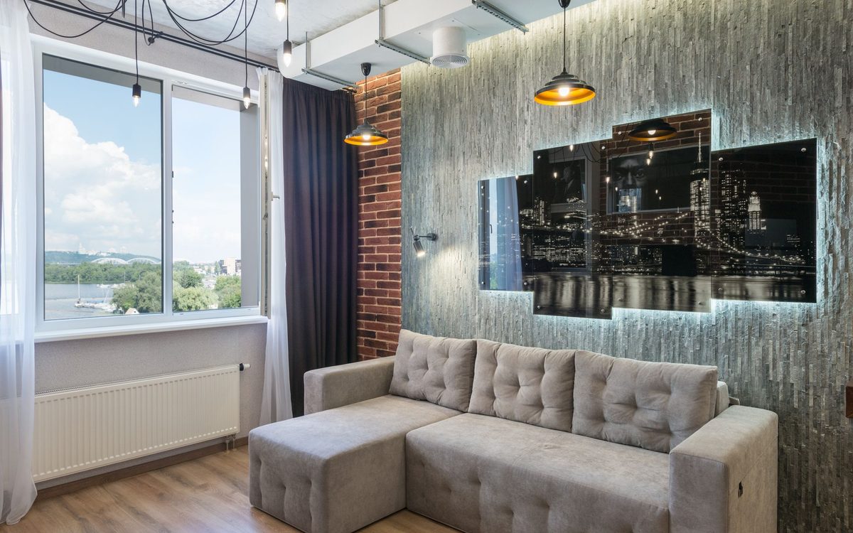 Stylish living room featuring a modern sofa, cityscape artwork, and large window with a scenic view.
